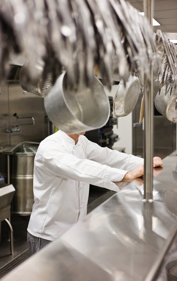 Chef leaning on shelf in commercial kitchen
