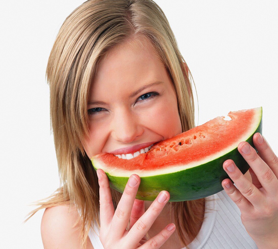 Junge Frau beisst genussvoll in ein Stück Wassermelone