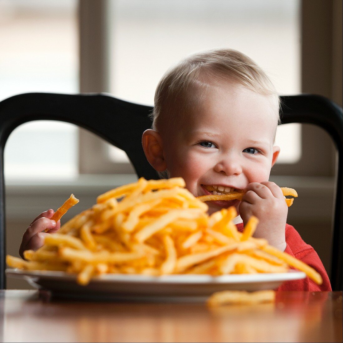 Kleiner Junge mit einer großen Portion Pommes frites