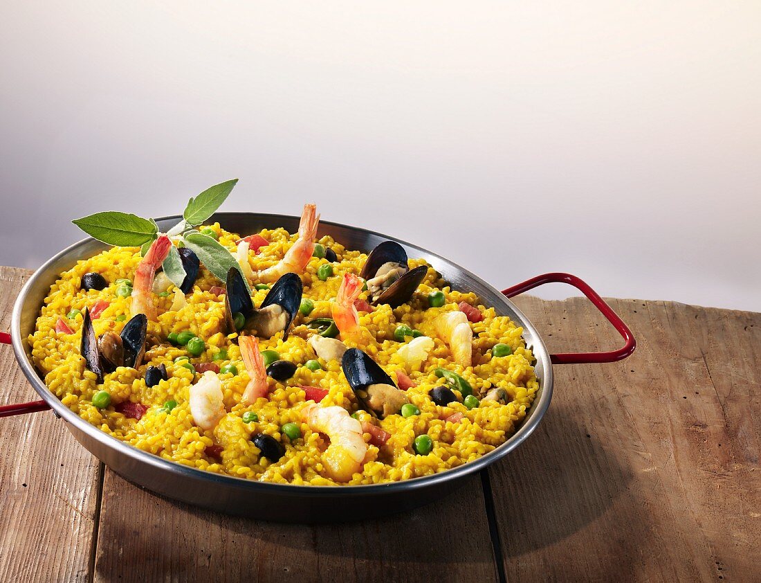 Paella in a pan on a wooden table