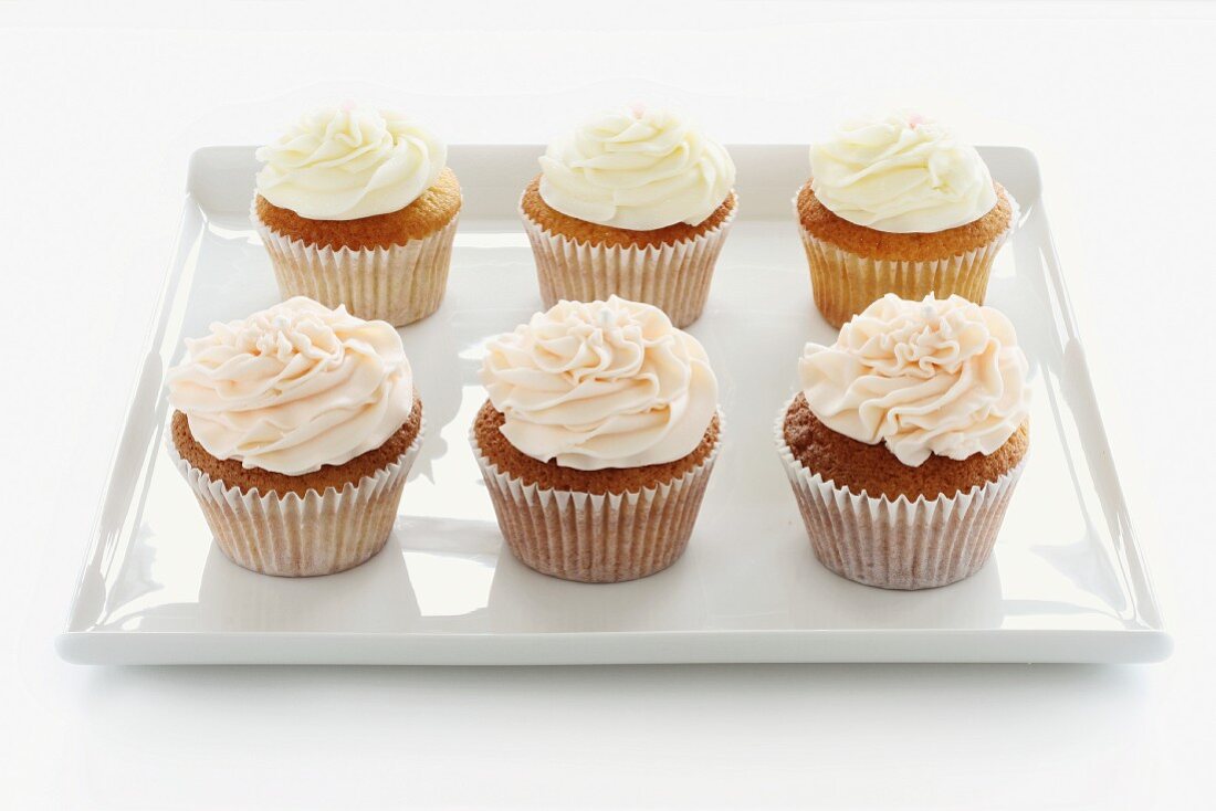 Six buttercream cupcakes on a square tray