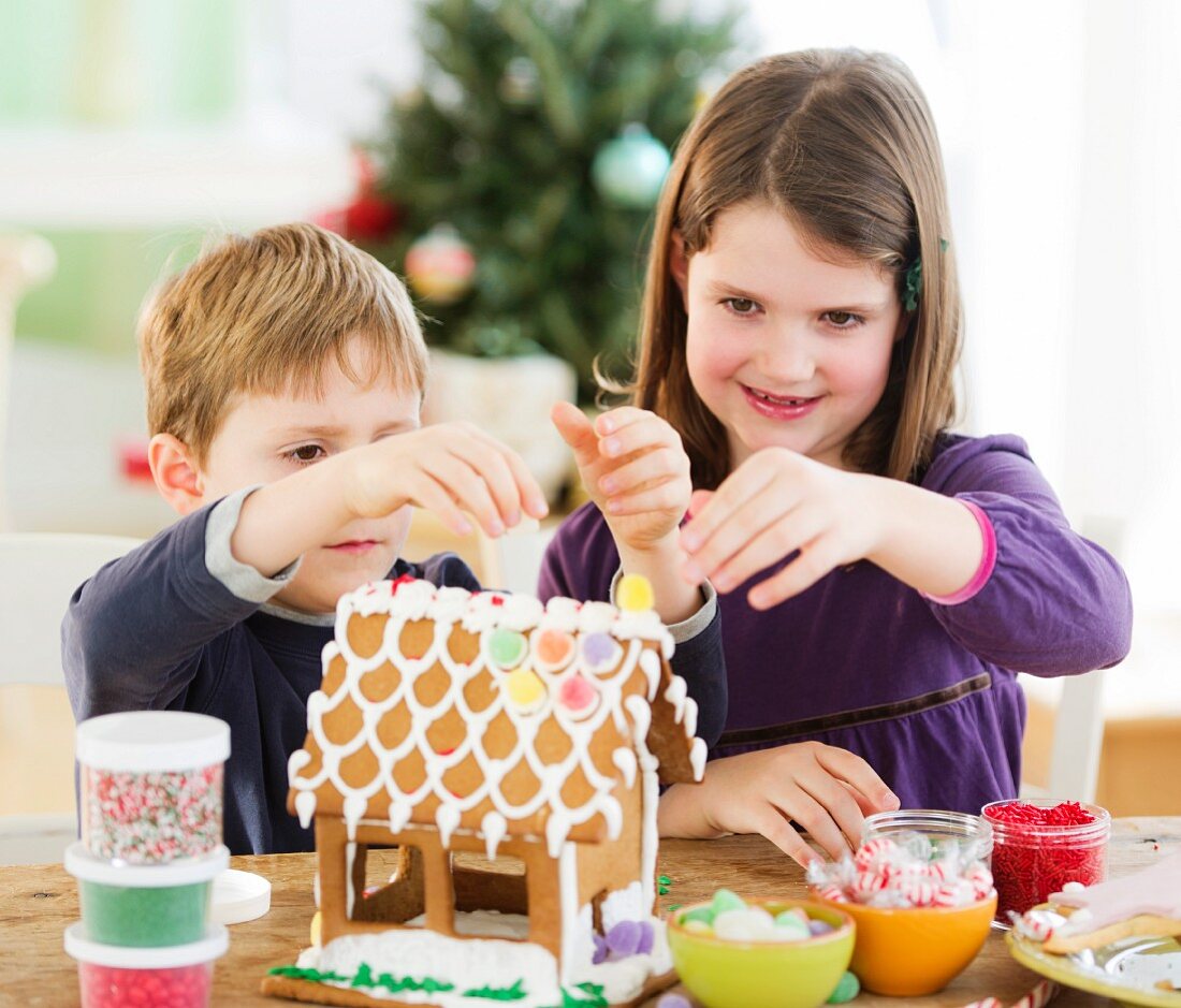 Girl (8-9) and boy (6-7) preparing gingerbread decorations
