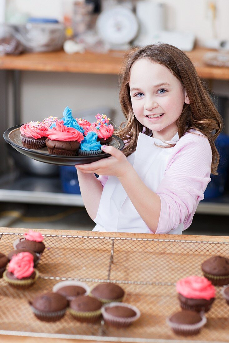 Young girl holding a plate of cupcakes