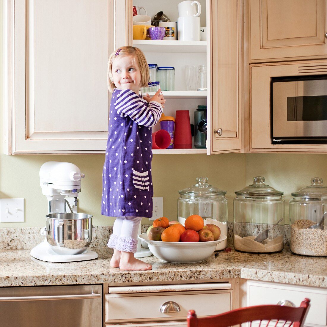 USA, Utah, Girl (2-3) climbing on cupboard in kitchen
