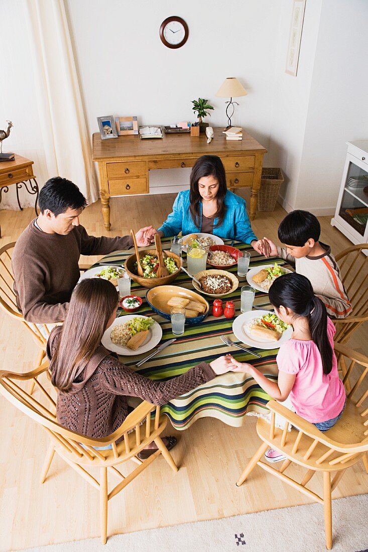 Familie mit drei Kindern beim Tischgebet