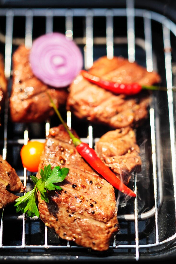 Beef with chili peppers and sliced onions on the electric grill