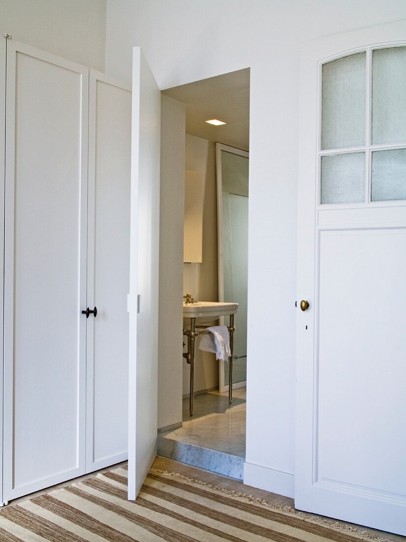 View through open dressing room door of vintage washstand in bathroom