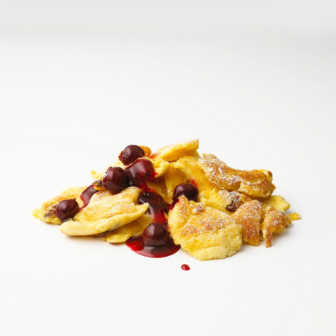 Kaiserschmarren (sweet cut up pancakes) with cherry compote in front of white background