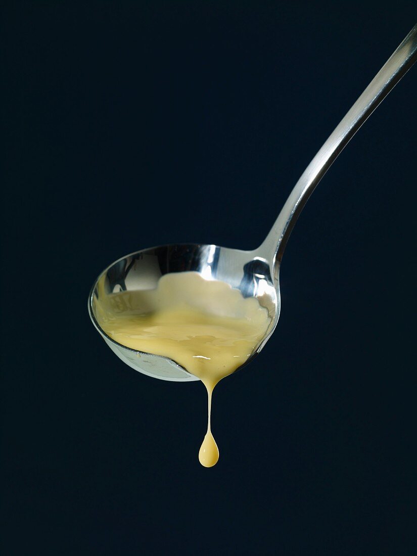 Vanilla sauce dripping from a ladle