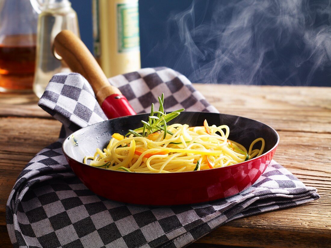 Spaghetti in the pan with zucchini and pepper strips
