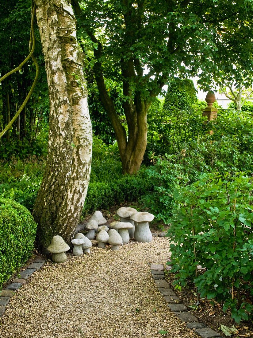 Gravel path & stone mushroom ornaments in garden