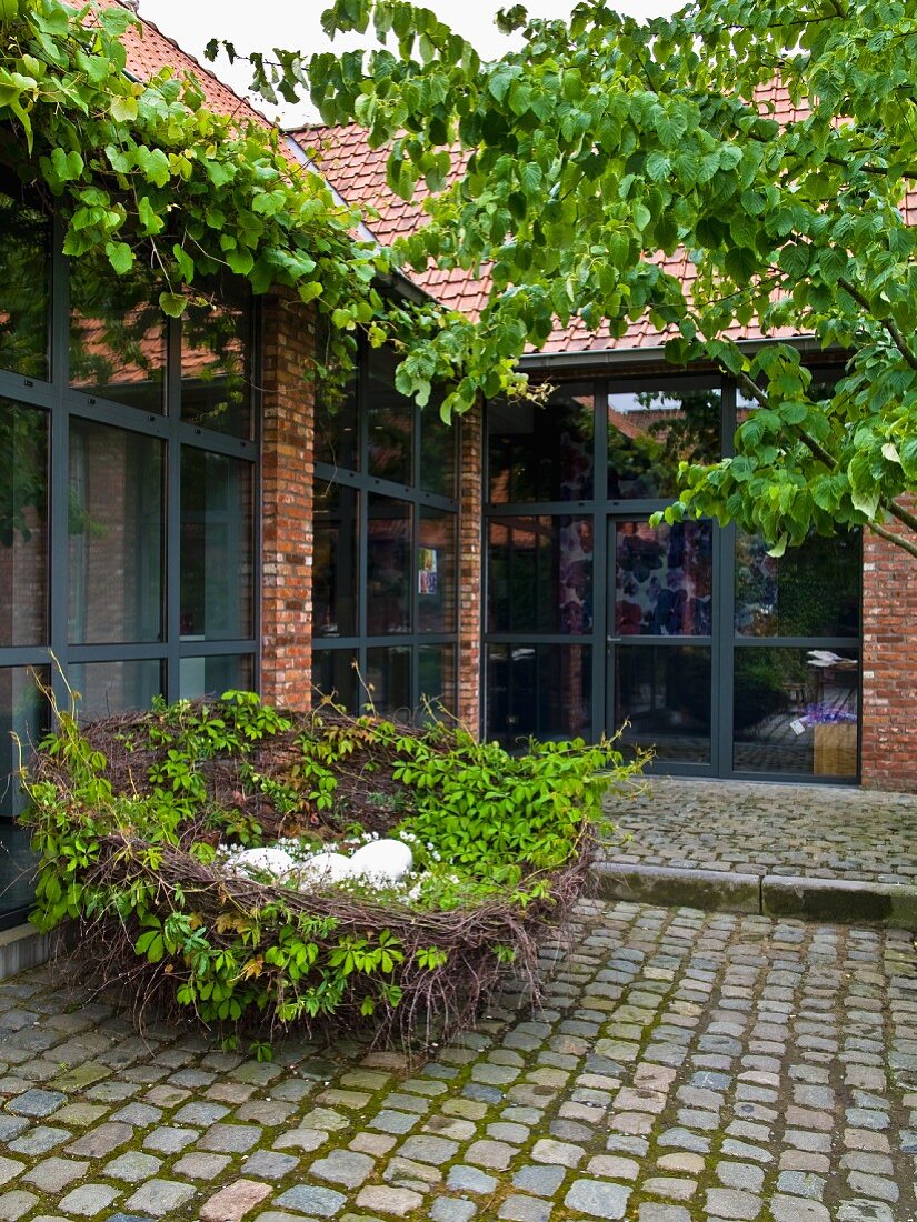 Large, decorative nest of willow whips in cobbled courtyard