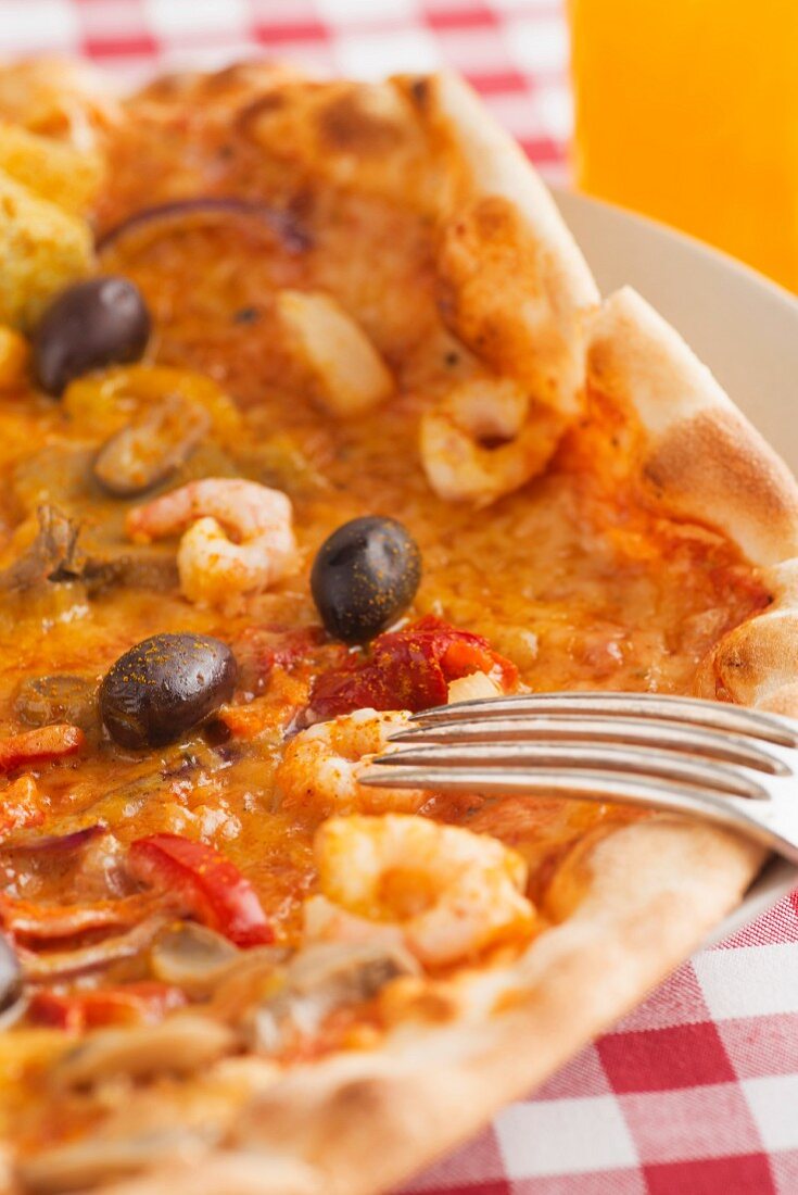 A pizza topped with vegetables, prawns and curry sauce