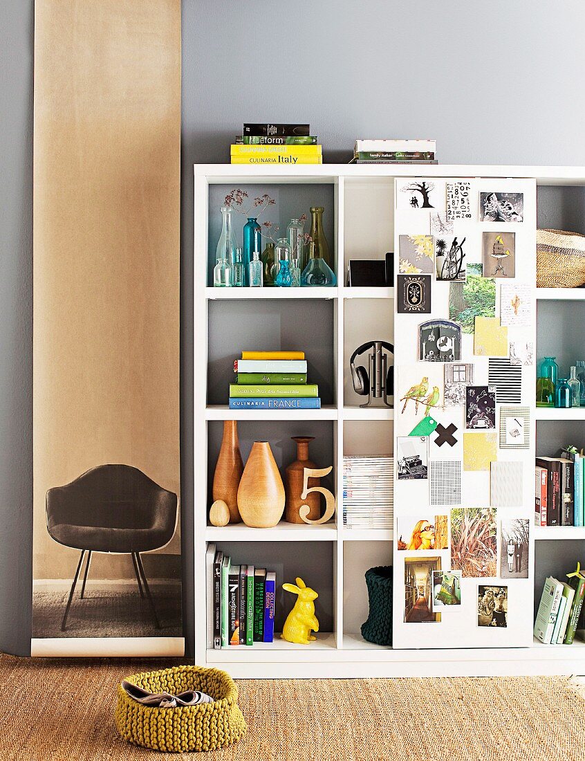 Shelving unit with single sliding door covered with pictures; photo of classic chair on long roll of paper decorating wall