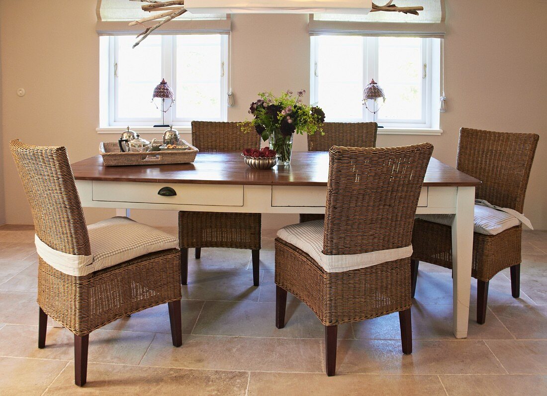 Rattan chairs around country-house table with white base and dark top