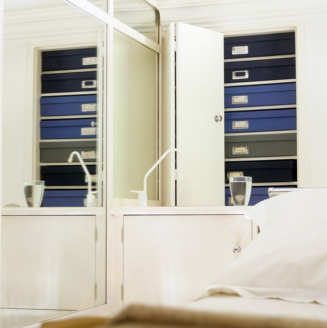 Pappschachteln in Blau und Grau hinter der Falttür eines Einbauschranks im Schlafzimmer