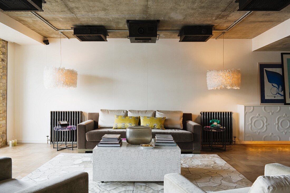 Loft-style interior with cubic coffee table in front of elegant sofa set flanked by designer lamps