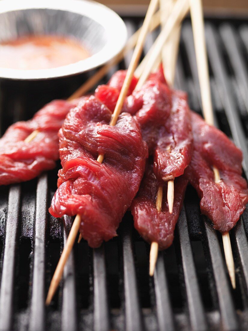 Raw satay skewers on the barbecue