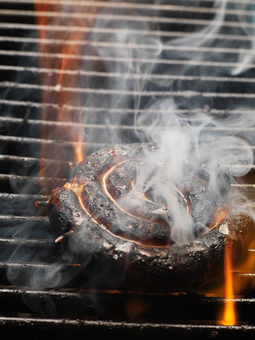 Verbrannte Bratwurstschnecke auf dem Grillrost