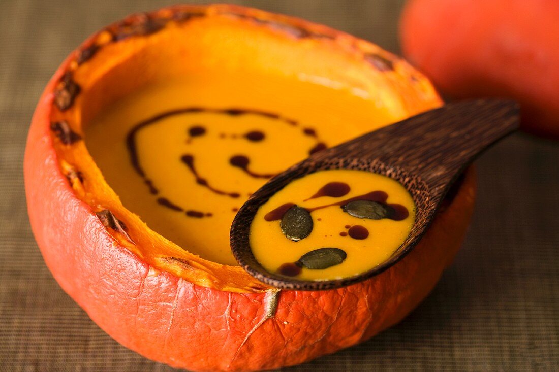Pumpkin soup in a scooped out pumpkin shell with pumpkin seeds