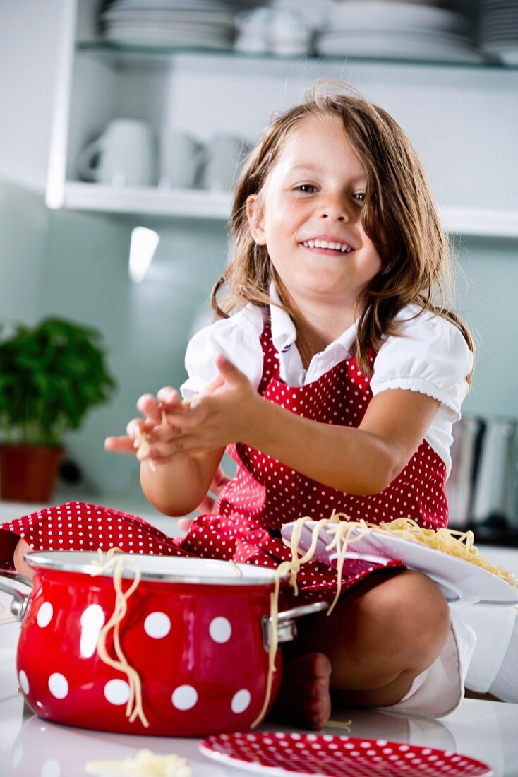 Germany, Girl playing with spaghetti, smiling, portrait