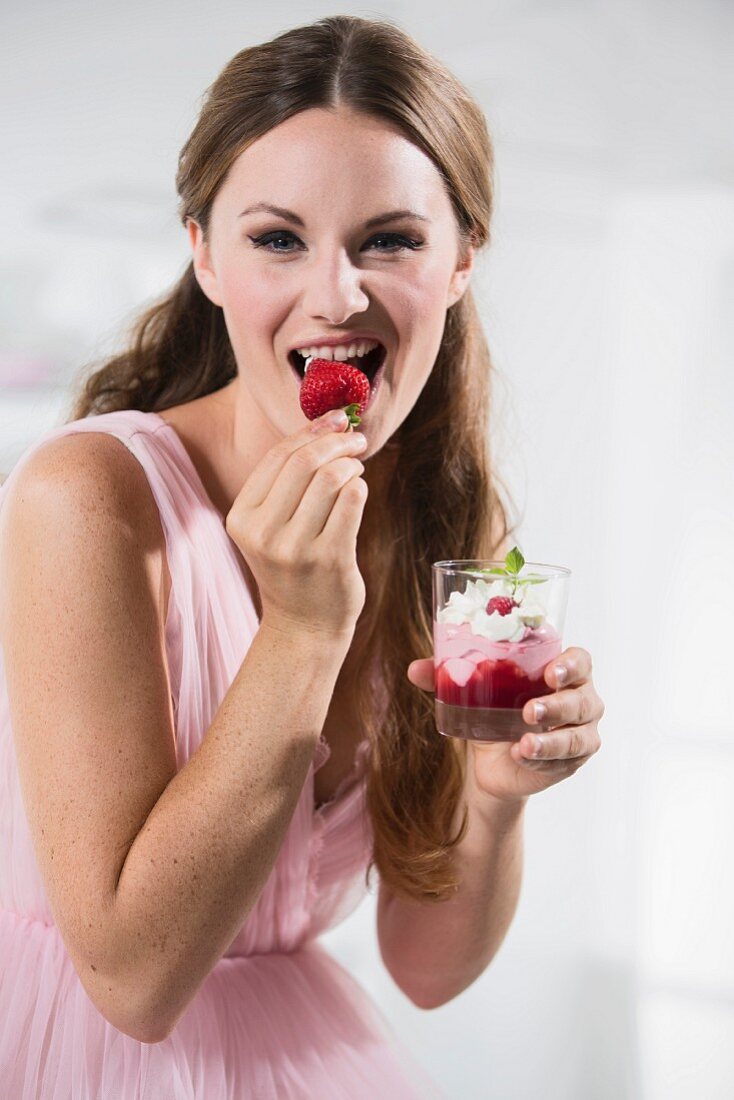 Young woman eating strawberry