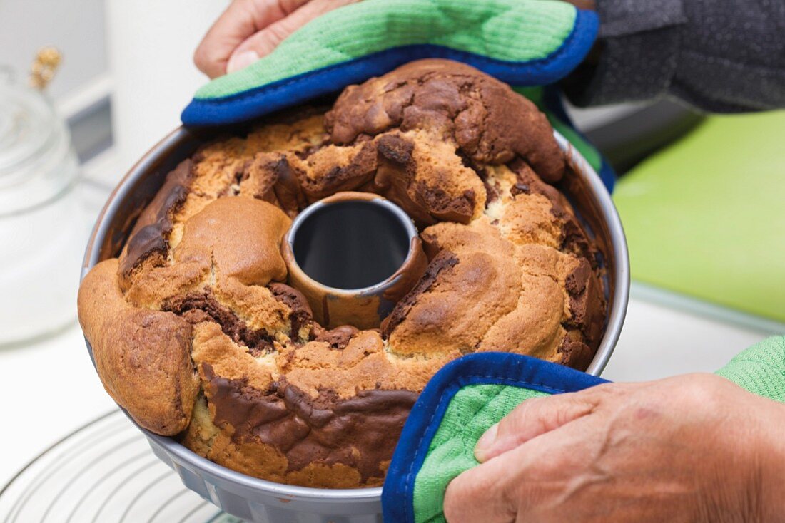 Hände halten Marmorkuchen in der Backform