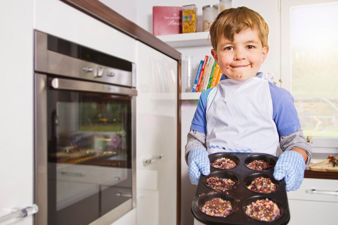 Germany, Boy baking cup cakes in tray, portrait