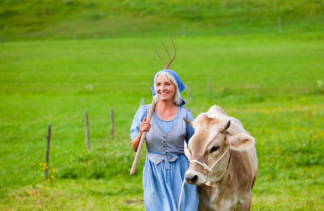 Germany, Bavaria, Mature woman with cow on farm