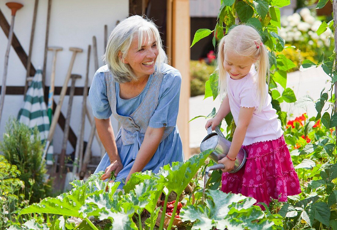 Germany, Bavaria, Mature woman and girl in graden caring for plants