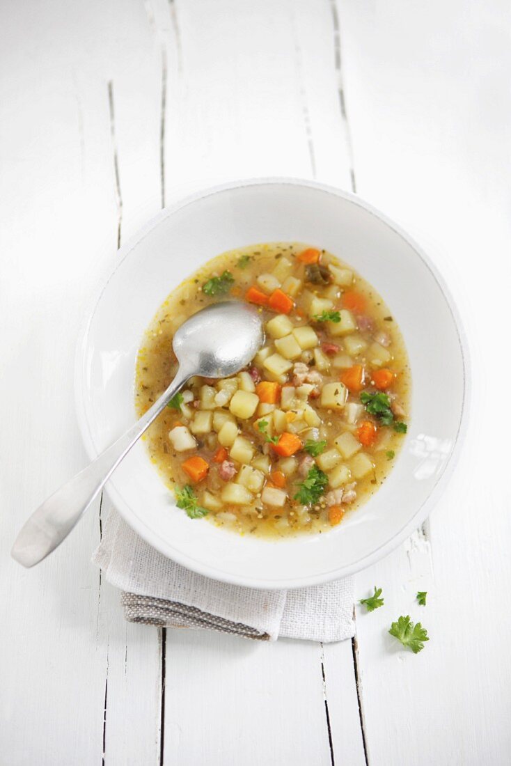 Bowl of potato soup with spoon on table