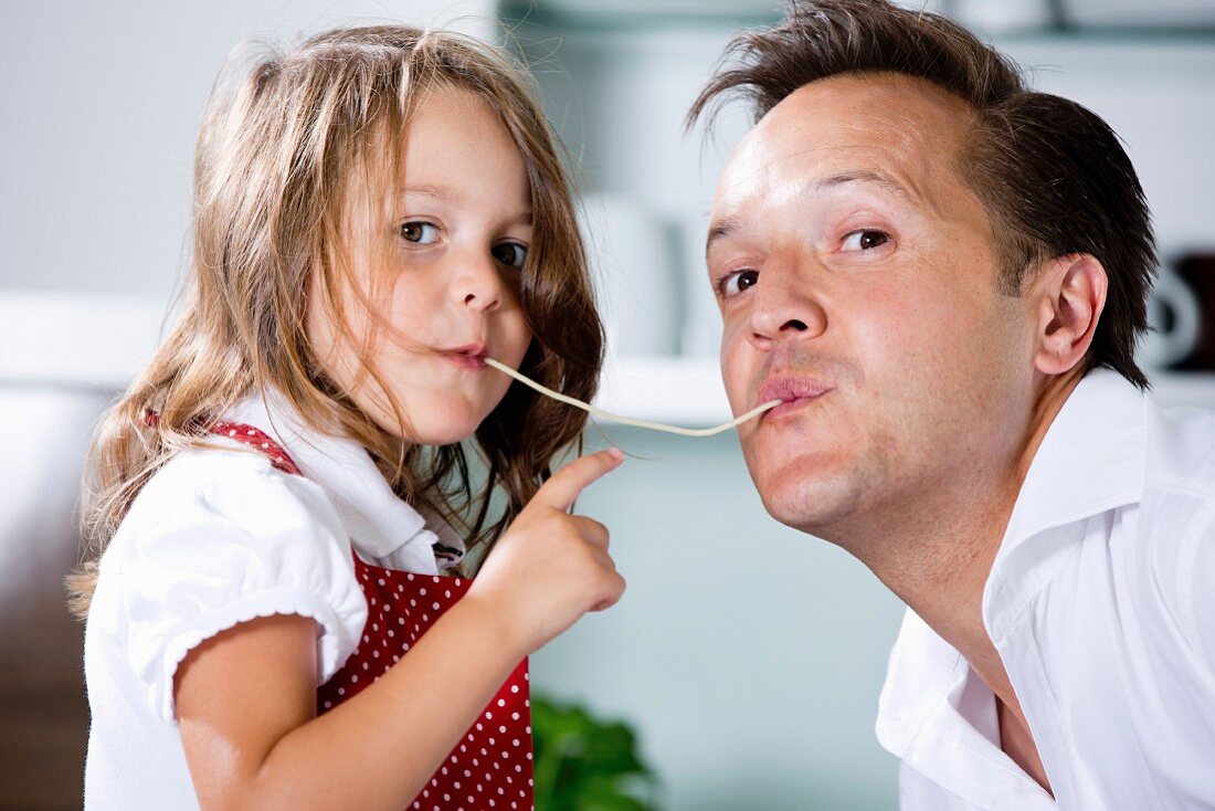 Germany, Daughter eating noodles with father in kitchen