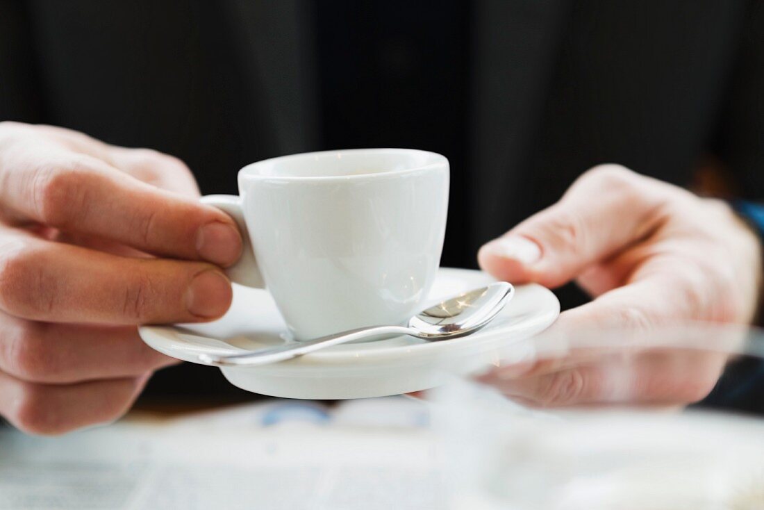 Hands holding an espresso cup