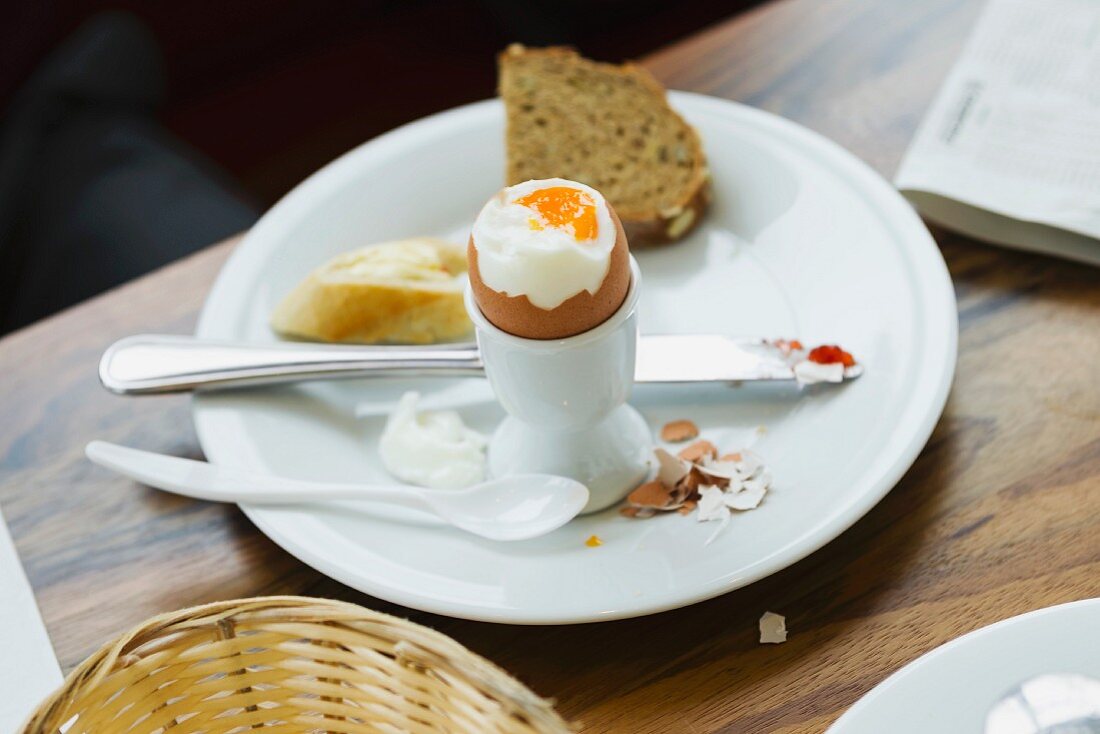 A soft egg in an eggcup and bread on a plate