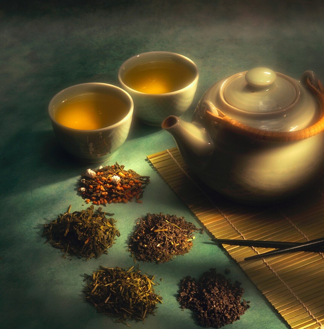 Verschiedene Grünteesorten; Teekanne und heißer Tee in Schalen