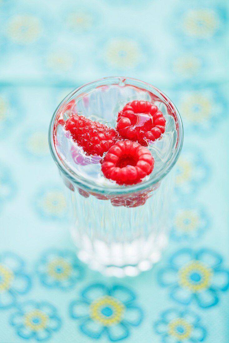 A glass of water with raspberries
