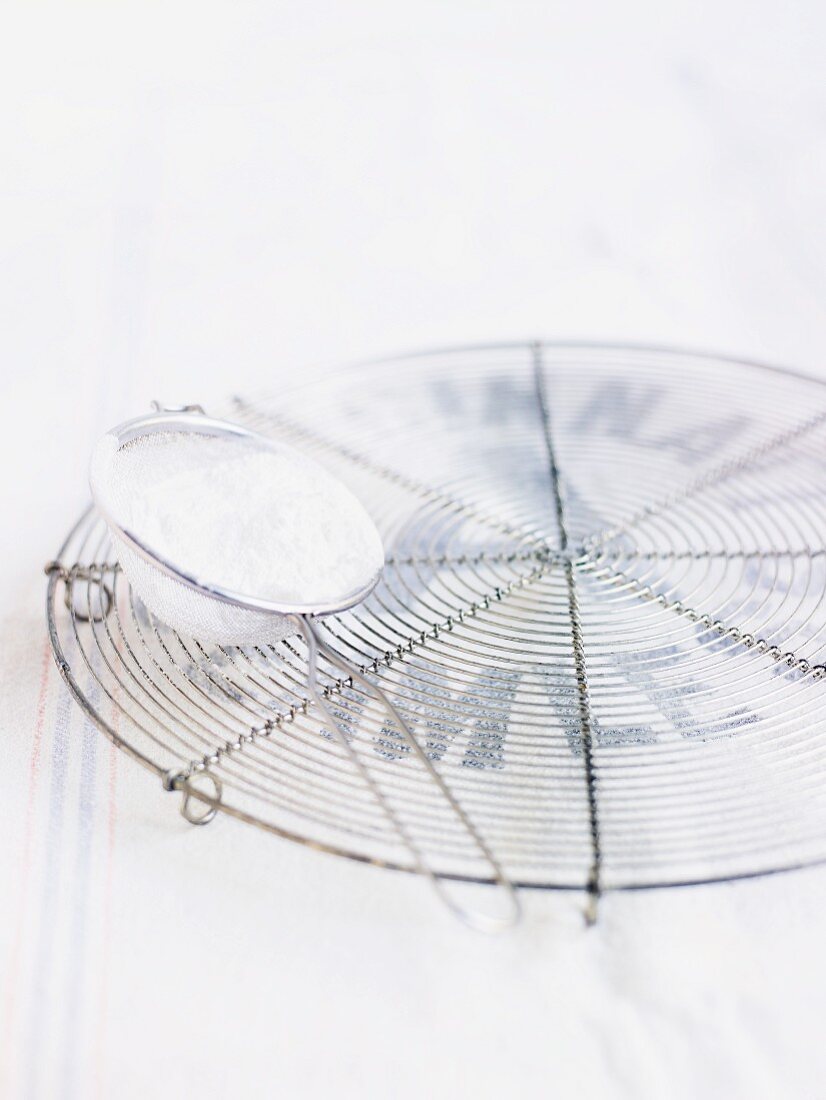 Icing sugar in a sieve on a cooling rack