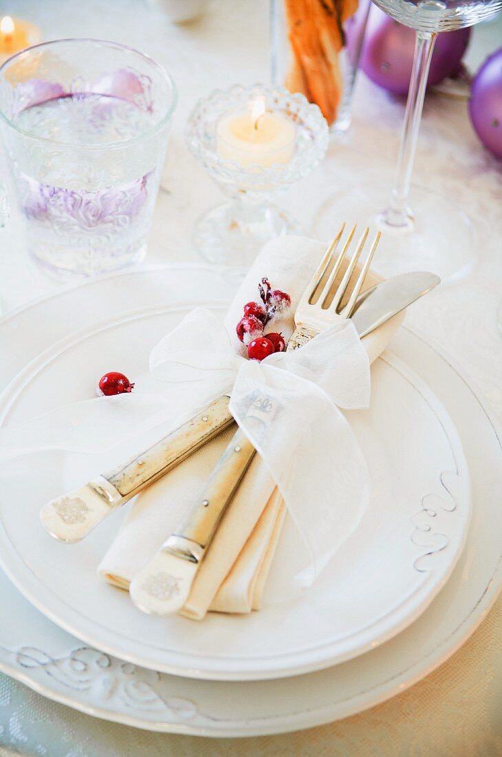 A Christmas place setting with cutlery, a napkin and a ribbon