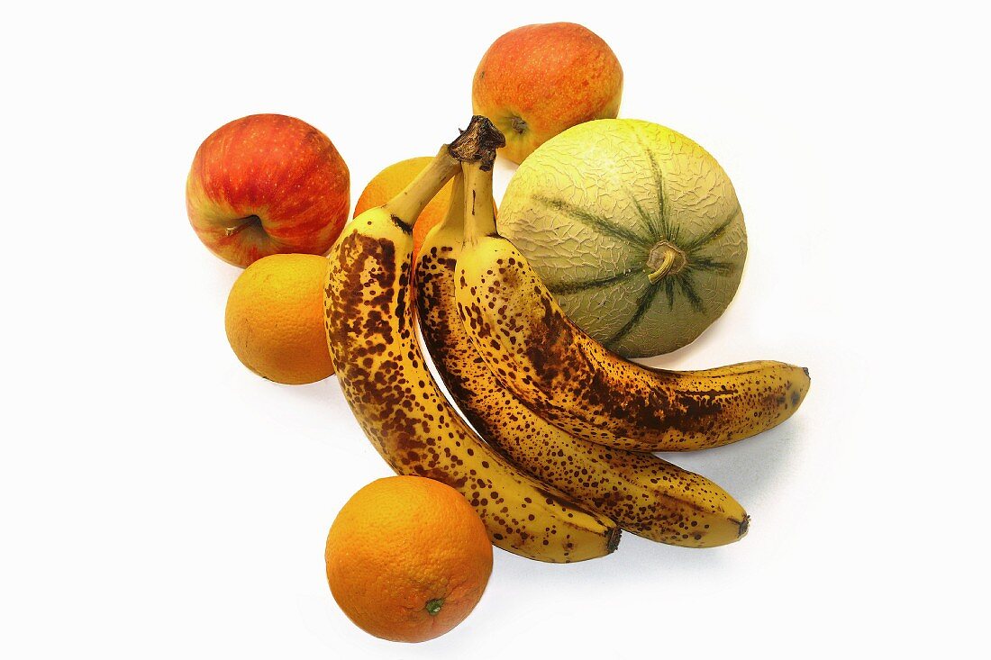 Apples, a melon, oranges and overripe bananas