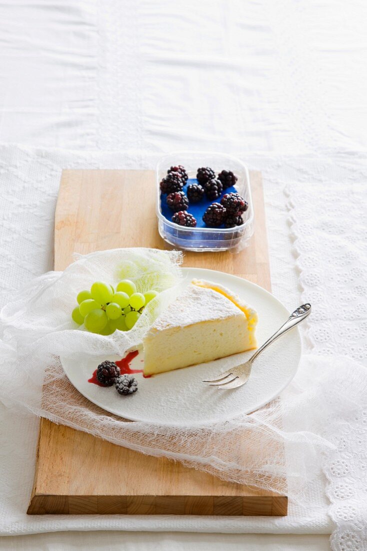 Ein Stück Käsekuchen mit Brombeeren und Trauben