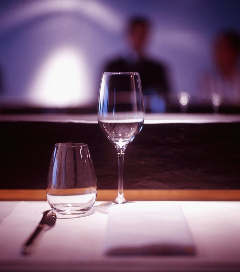 An empty wine glass and a water glass on a restaurant table