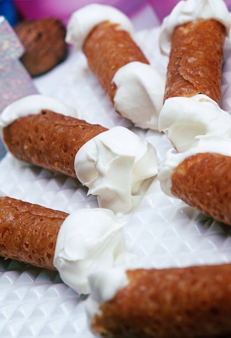 brandy snaps filled with cream on a white plate