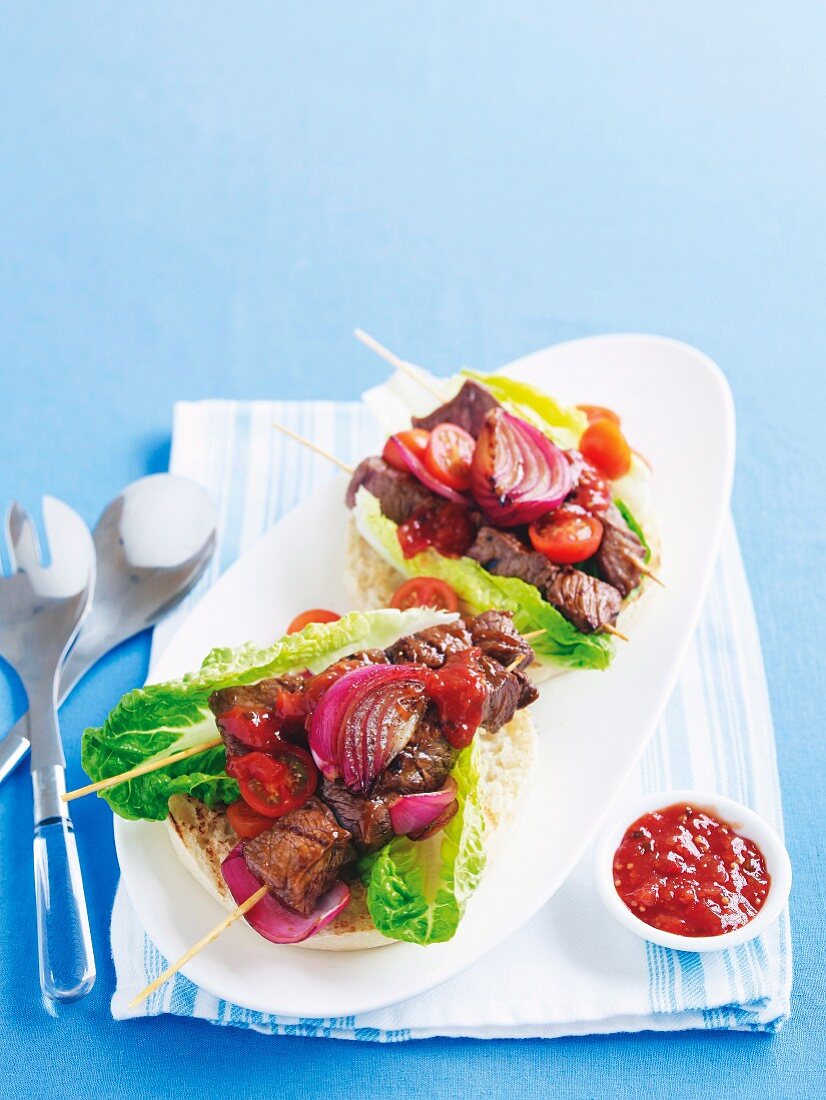 Marinated beef skewers with salad on a grilled roll, served with tomato chutney