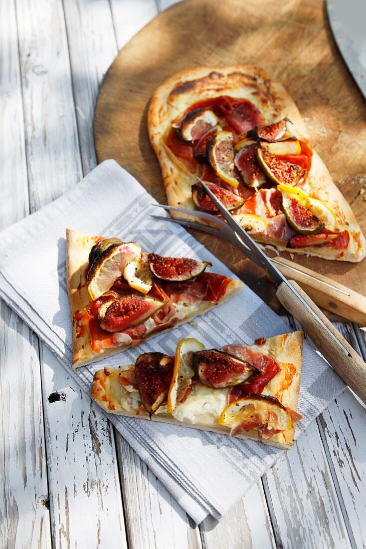 A long thin pizza topped with ham and figs