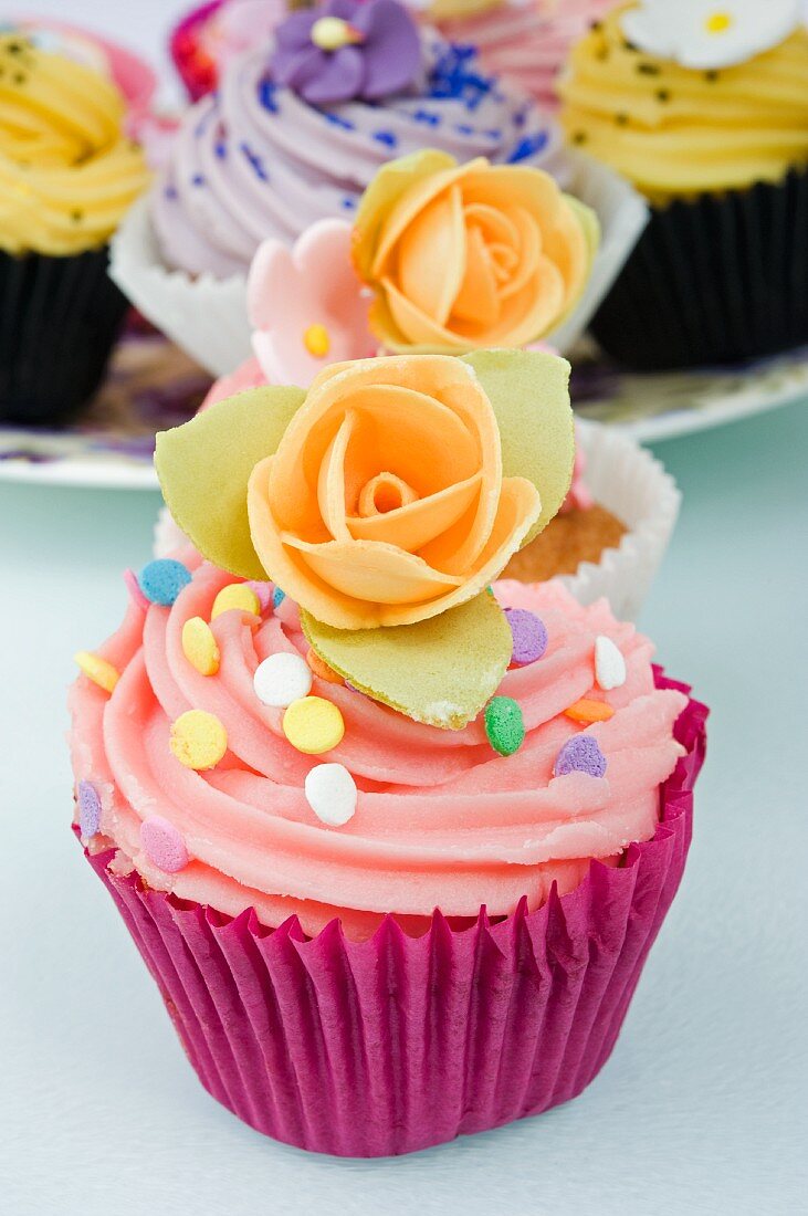 Mehrere Cupcakes mit Zuckerblumen und Zuckerkonfetti