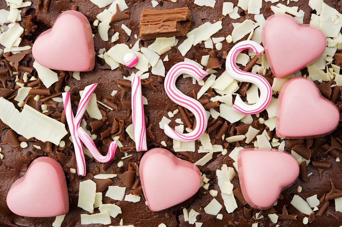 still life of pink heart shaped chocolates with the word kiss in stripy pink candy
