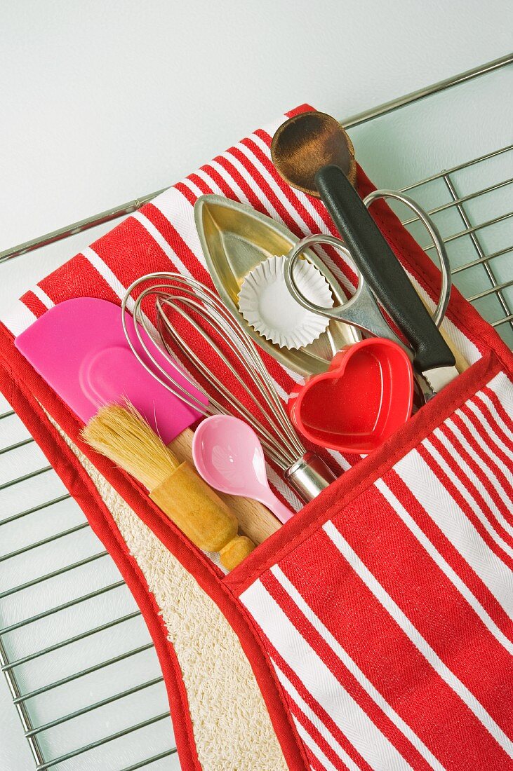 Rot-weiss gestreifter Handschuh mit Kochutensilien auf einem Abkühlgitter