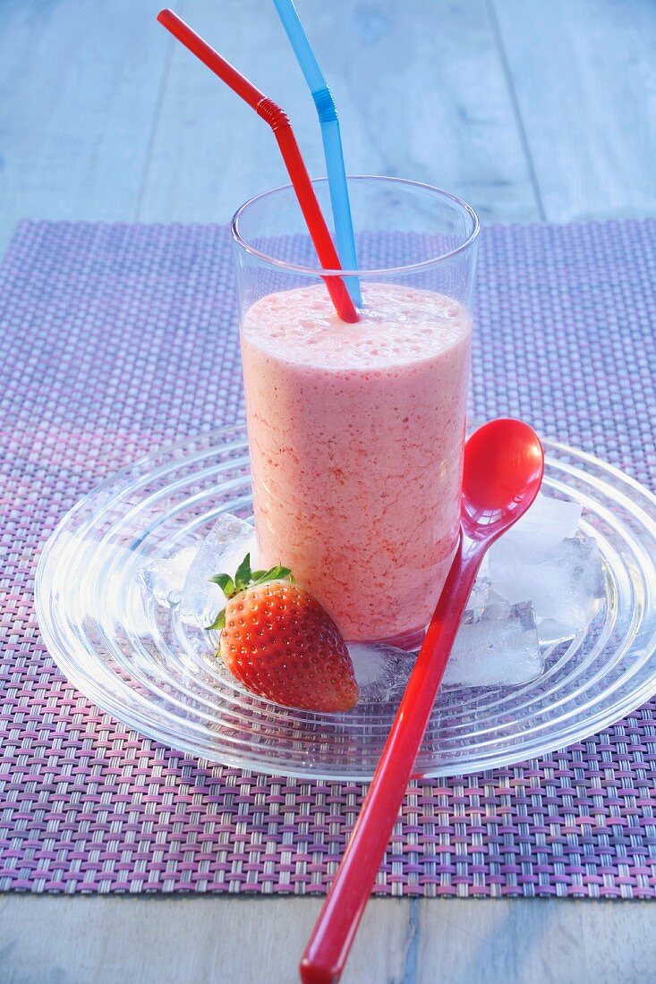 Strawberry milkshake in a glass with drinking straws