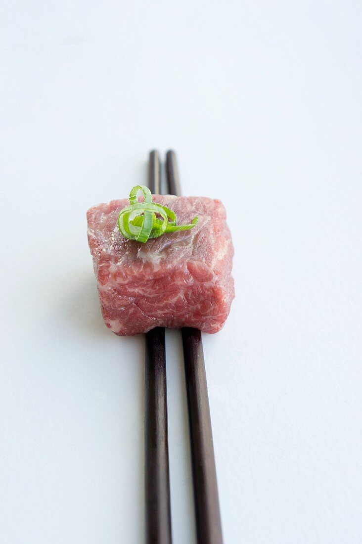 Wagyu beef on chopsticks with sliced spring onions (Negi)