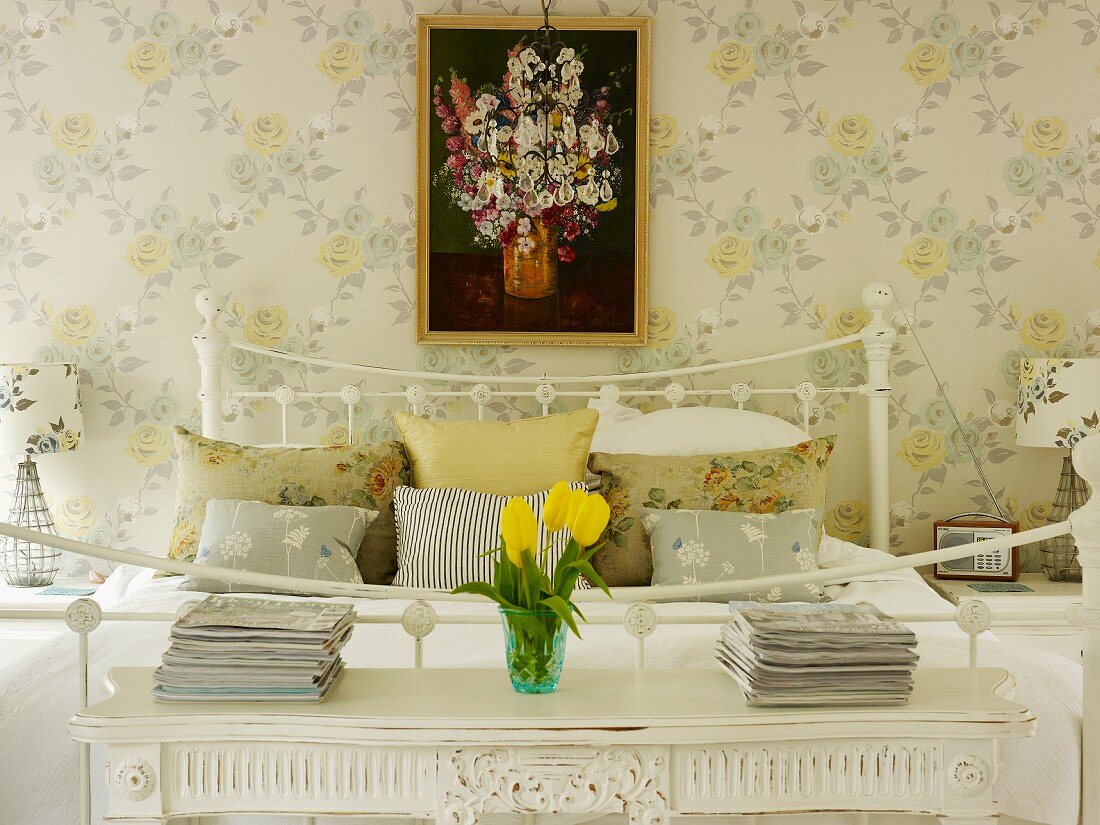 Romantic bedroom with bedside tables, floral wallpaper and picture of flowers